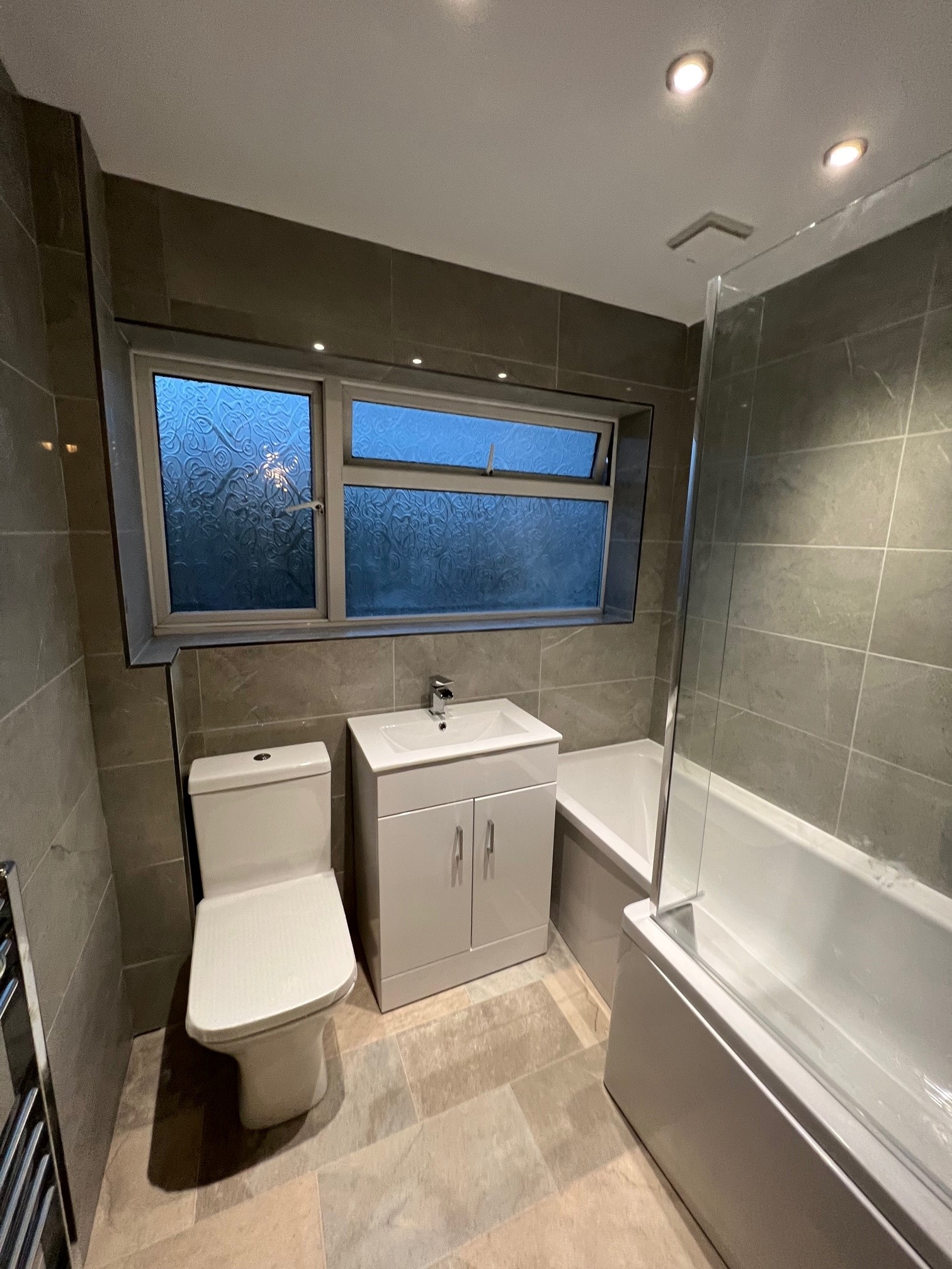 Tiled bathroom with L shaped bath and dual outlet shower